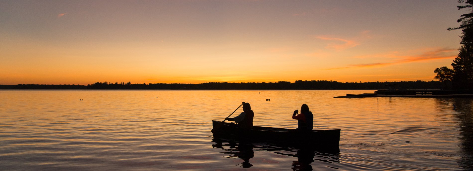 two people in canoe on a lake before dusk